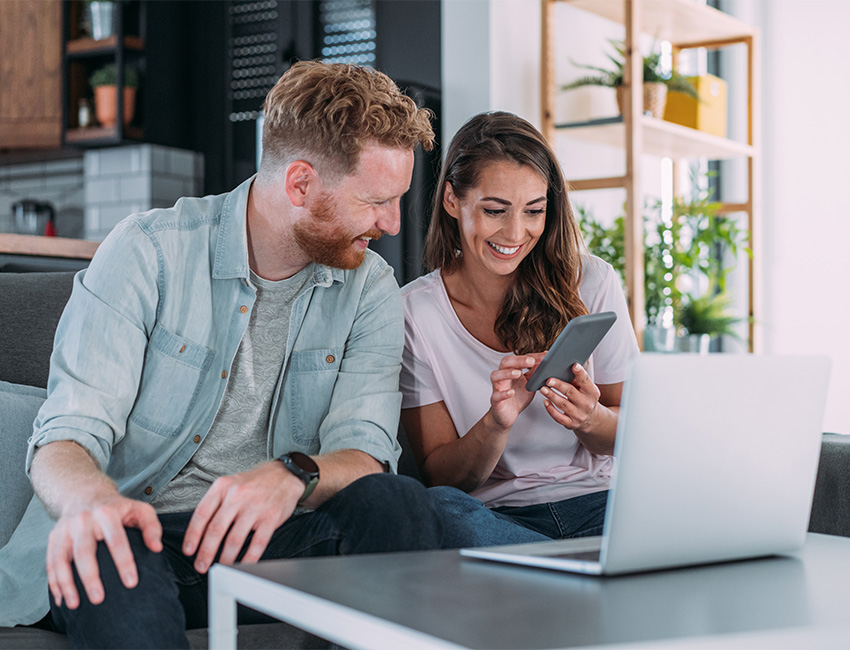 Two people looking at phone and laptop