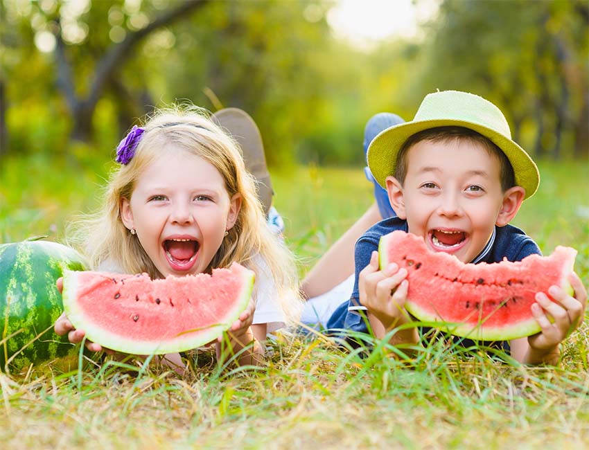 Two kids smiling and eating watermelon