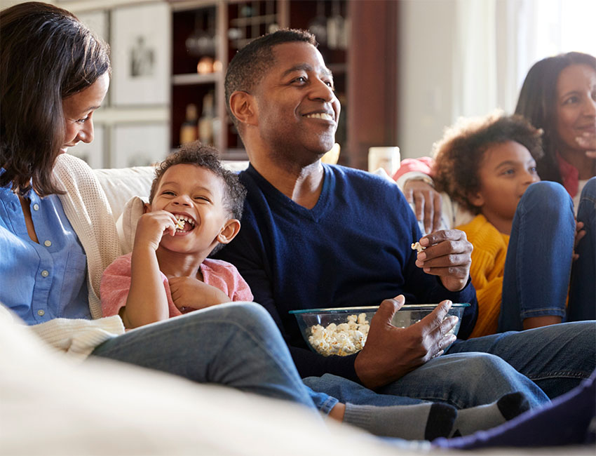 Happy family sitting on couch eating popcorn