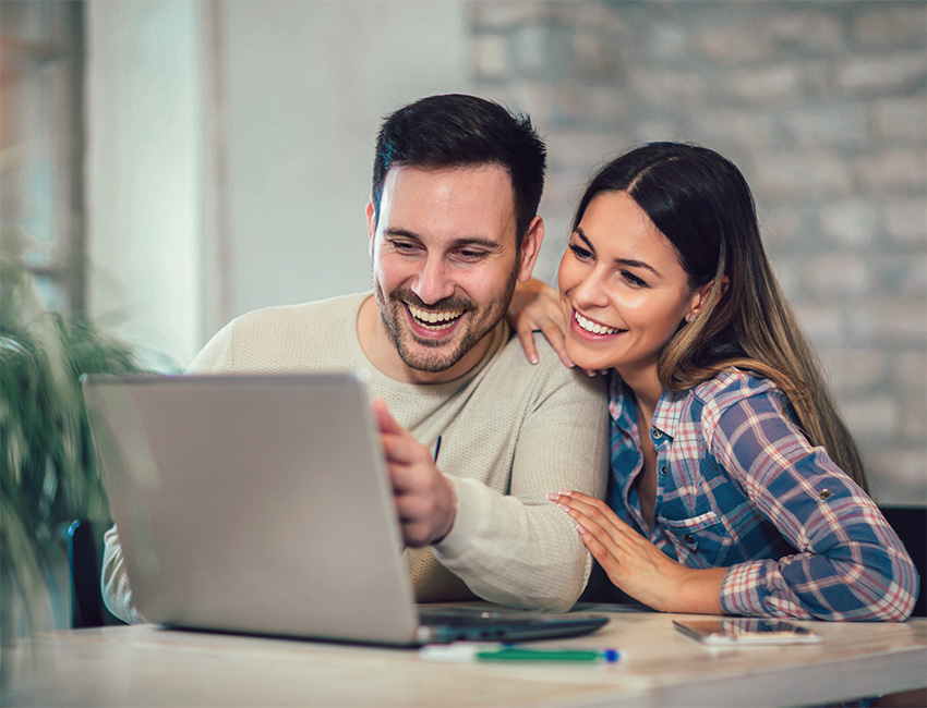 Happy couple looking at laptop