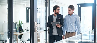 two businessmen using a digital tablet together in an office