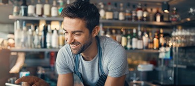 Man smiling and looking at a tablet in his store