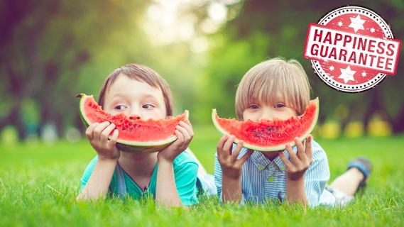 Happy kids eating watermelon on the grass.