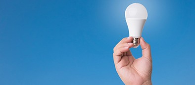 a hand holding a lightbulb against a blue background